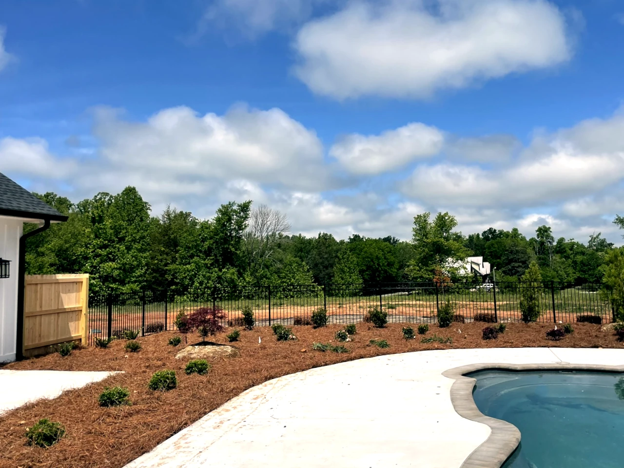 Newly installed residential landscape with a variety of shrubs near a pool in Winston-Salem, NC by GH Cutting Edge