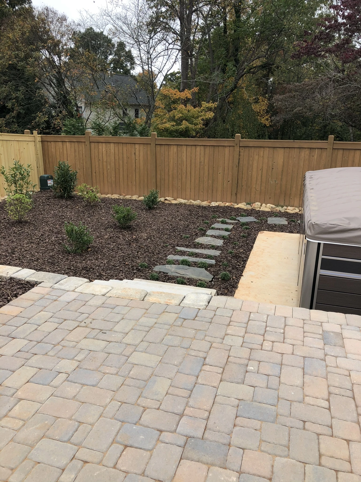 Hardscaping design featuring patio pavers and stepping stones with landscaped garden beds in Winston-Salem, NC by GH Cutting Edge.